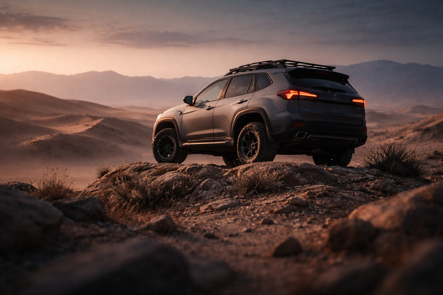 Low-angle photograph of an unbranded rugged hybrid SUV silhouetted against a dusky sky atop a rocky outcrop, with sweeping desert dunes and warm rim light; the lower third is intentionally uncluttered.